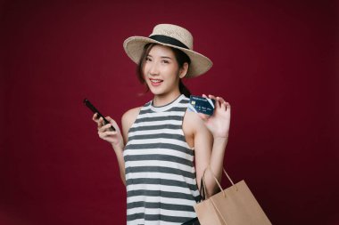 Güzel Asyalı bir kadının portresi. Şapka takıyor. Kredi kartıyla internet üzerinden alışveriş yapıyor..