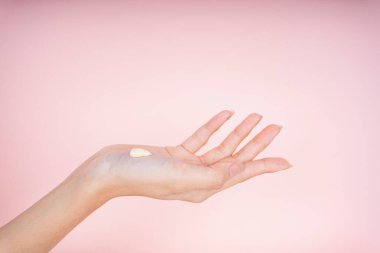 Güzel bir kadının ellerinin krem losyonlu yakın plan görüntüsü pembe arka planda izole edilmiş..