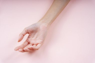 Kadın eli açık pembe arka planda bir jest gösteriyor.