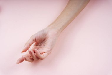 Kadın eli açık pembe arka planda bir jest gösteriyor.