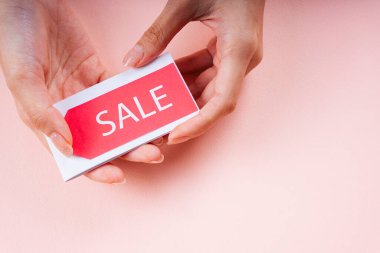 Pembe arka planda satış etiketi tutan bir el..