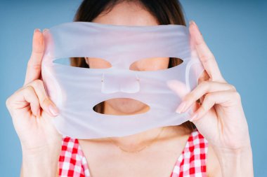 Güzel genç Asyalı kadın yüzünü nemli tutmak için maske kullanıyor..