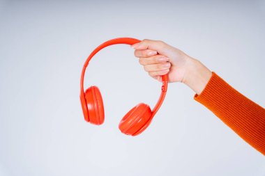 Kırmızı kulaklık tutan kadın elleri beyaz arkaplanda izole edilmiş..