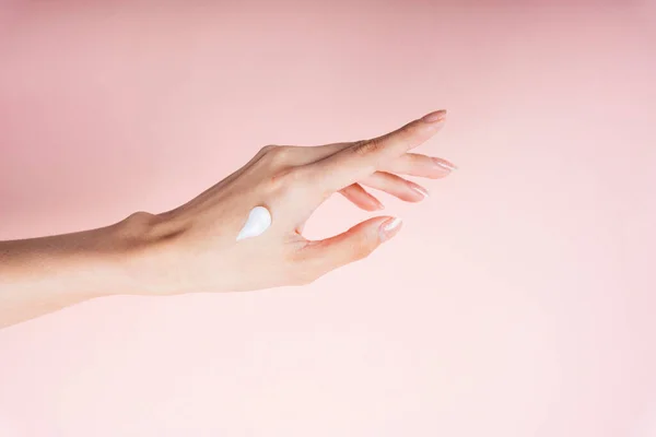 Woman hand applying lotion cream isolate on pink background.