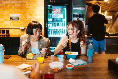 Genç Asyalı iş adamları mutfakta yemek molası veriyor..