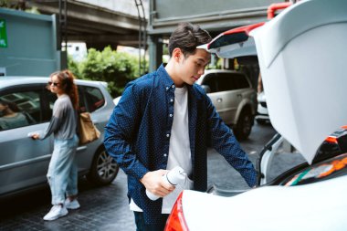 Asyalı adam yolculuktan önce bagaja bavul koyuyor..