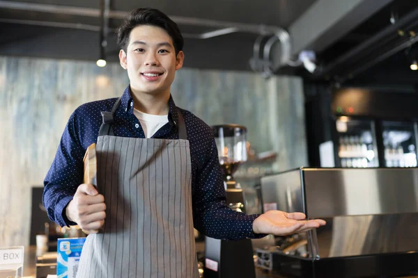 Portrait of young asian waiter holding wooden tray show hand empty hand for product.