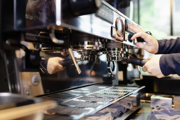 Close up hand of barista making coffee with machine in cafe.