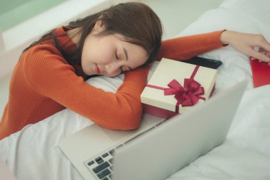 Genç güzel Asyalı kadın Noel günü dizüstü bilgisayarın önünde uyuyan siyah saçlı..