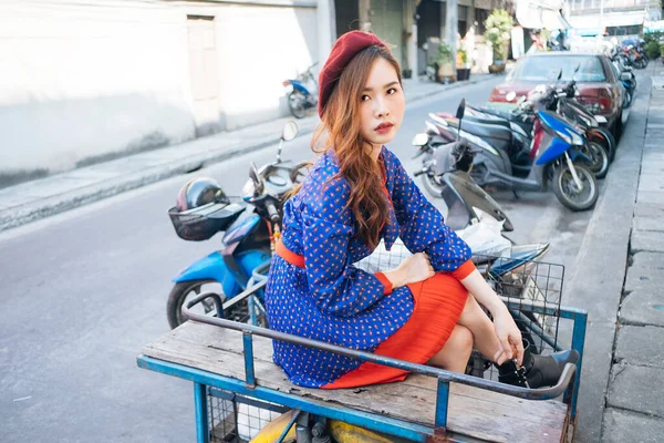 波ブルネット女性で青と赤のレトロドレス座っています上のボックスバイクで通り — ストック写真