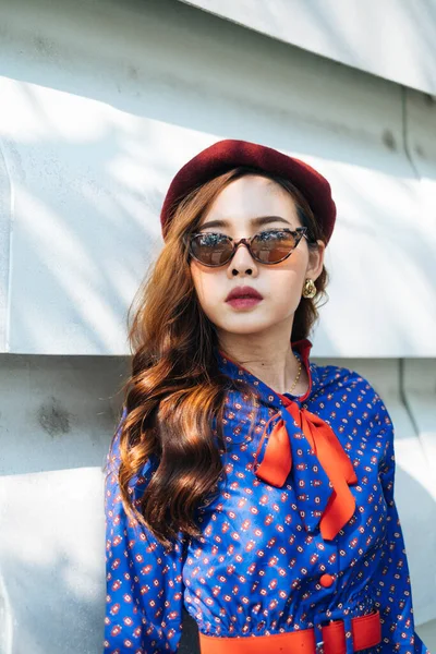 Mavi ve kırmızı retro elbiseli dalgalı esmer kadın beyaz katman duvarında duruyor, gökyüzüne bak..