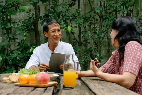 Old asian couple having breakfast together at backyard in holiday.