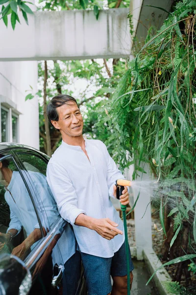 自宅の庭で引退したアジア人の男性散水工場 — ストック写真