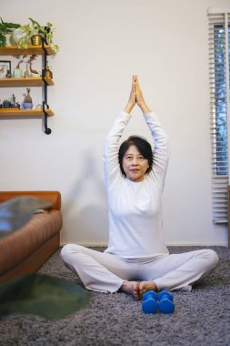 Asyalı son sınıf öğrencisi evde yoga yapıyor. Sağlıklı yaşam tarzı kavramı.