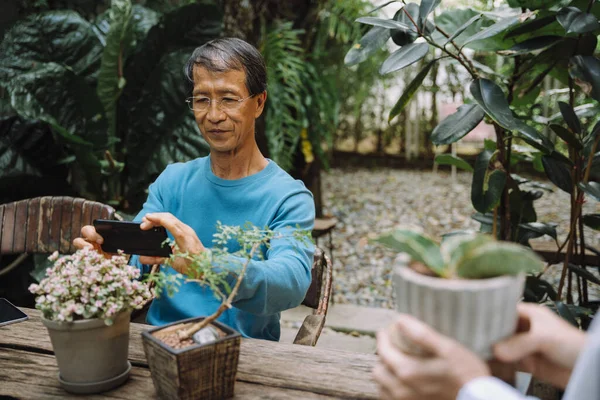 Ásia Sênior Homem Tomando Foto Bonsai Flor Pote Com Smartphone — Fotografia de Stock