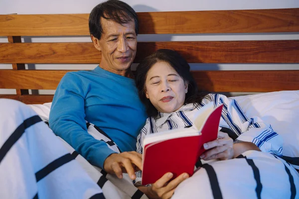 アジアの高齢者のカップル一緒にベッドルームで本を読んで — ストック写真