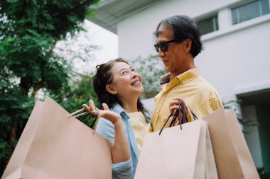 Asya 'lı kıdemli karı koca alışveriş poşetleri taşıyor..