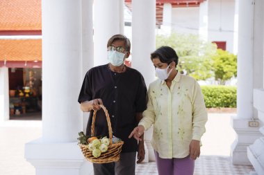 Asyalı yaşlı bir çift, bir meziyet için tapınakta maske takıyor..