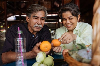Neşeli Asyalı kıdemli ihtiyarlar tapınakta sadaka vermek için hazırlık yapıyor..