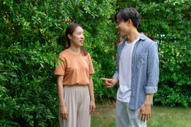 Bahçede birbirleriyle konuşan neşeli Asyalı genç çift..