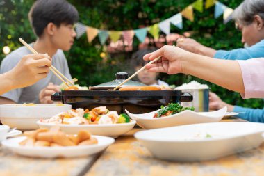 Asyalı aile, özel bir olayı kutlamak için bahçede barbekü yemeği yemeyi sever..