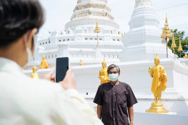 アジアの高齢者のカップルは タイの寺院でスマートフォンで写真を撮るマスクを着用 — ストック写真