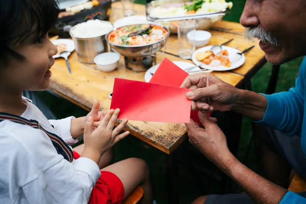 Avô Dando Envelope Vermelho Para Filho Mais Novo Família Festa — Fotografia de Stock