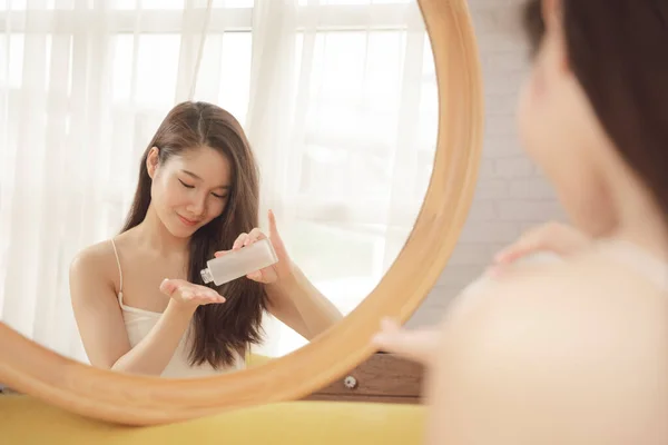 아시아인 미녀가 거울에 크림을 바르고 있어요 스킨케어 — 스톡 사진