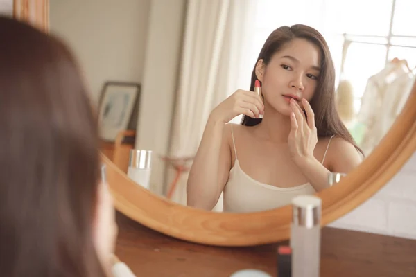 若いですアジアの美しさ女性Applyin作ります口紅で化粧品デスク — ストック写真