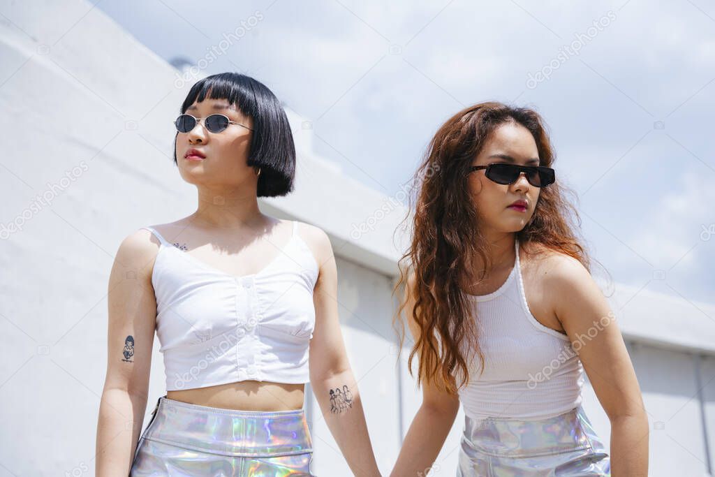 Portrait of two young asian women wear white vest and sunglasses on street.