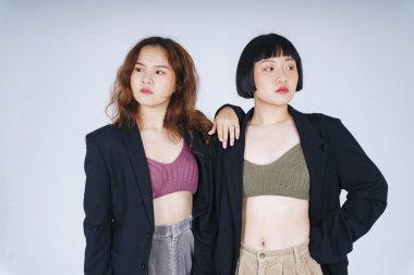 Siyah ceket giyen iki Asyalı kadının portresi beyaz arka planda izole edilmiş..