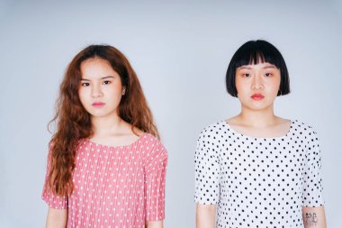 Beyaz ve pembe palkadot giymiş iki Asyalı kadının portresi beyaz arka planda izole edilmiş..