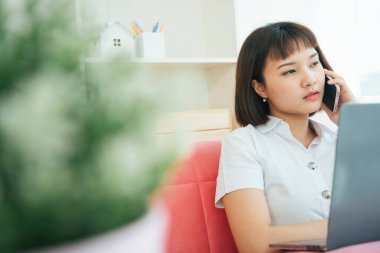 Covid-19 salgını sırasında arkadaşınla evde akıllı telefondan konuşarak Tayland üniversitesi öğrencilerinin çalışmalarını izliyorsun..