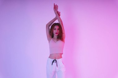 Aktif Asyalı kıvırcık saçlı kız stüdyoda neon ışıkta dans ediyor..