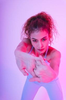 Genç ve sağlıklı Asyalı kıvırcık saçlı kadının yakın portresi egzersizden önce ellerini ısıtıyor..