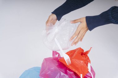 Plastik torba atıklarını geri dönüştüren bir kadın eli beyaz arka planda izole edilir.