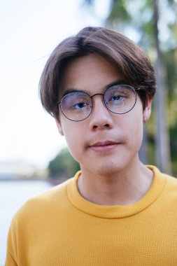 Sarı tişörtlü ve mavi pantolonlu adamın parkta gözlük taktığı yakın plan fotoğrafı..