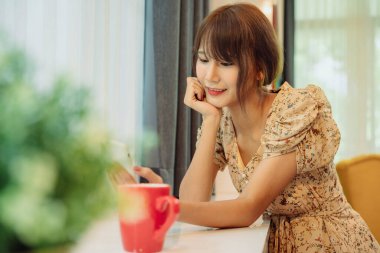 Güzel Asyalı Taylandlı kadın evde internet hizmeti için akıllı telefon kullanıyor..