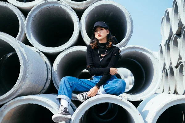 Fashionista Chica Suéter Negro Gorra Jeans Sentado Solo Tubo Hormigón — Foto de Stock