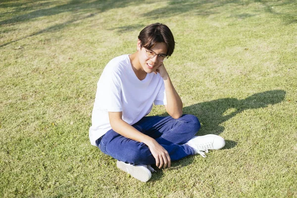 Black Hair Guy White Shirt Eyeglasses Sitting Grass Field Sunlight — Stock Photo, Image