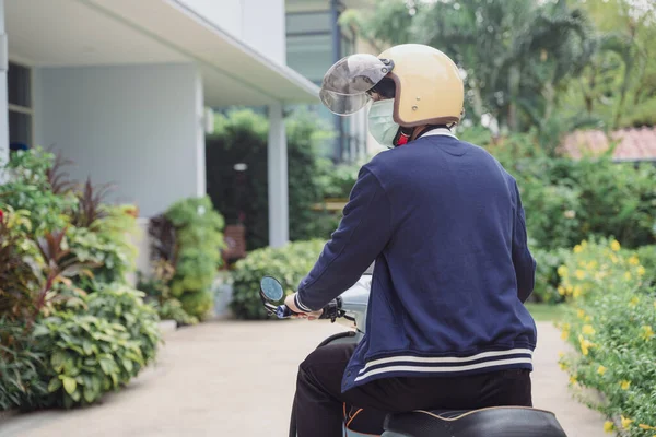 Motorbike delivery man wearing mask deliver food finding home.