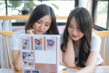 Beyaz tişörtlü iki kız kafede oturup içki hakkında konuşuyorlar..