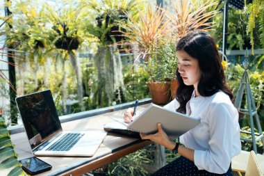 İş adamı tahta masaya defter yazıyor. Açık hava çalışma konsepti.