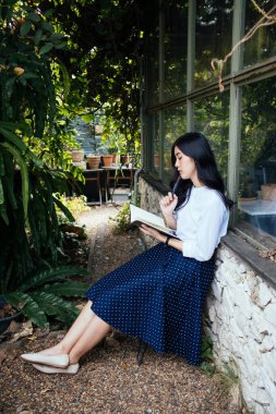 Genç Asyalı kadın bir kitaba yazmadan önce konsepti düşün. Kadın roman yazarı hikayenin bir sonraki bölümünü düşünüyor..