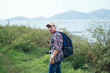 Erkek maceracı ağaç, göl ve dağla doğal patikada yürüyor..