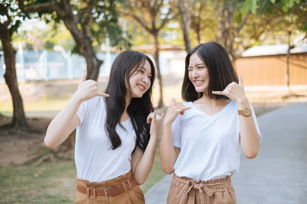 公園に立っている白いTシャツと茶色のパンツの2人の陽気な女の子は お互いを見て笑顔 — ストック写真