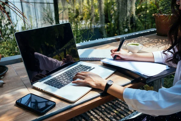 Business woman working on paper and laptop to gather information on working desk.