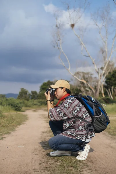 Male adventurer enjoy walking in the natural trail in sunny day with his camera to take a photo of nature.