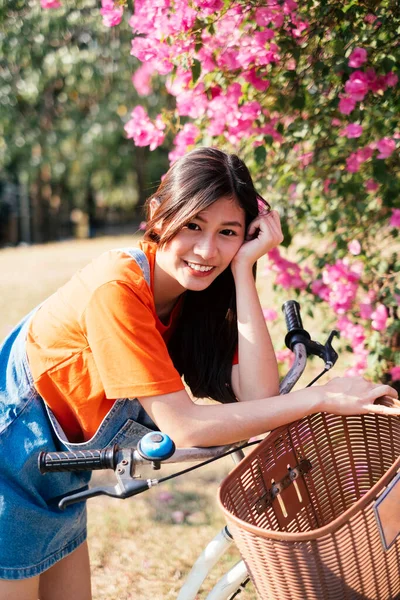自転車でピンクのブーゲンビリアで自転車を停止し 彼女の体を曲げますオンザバイク — ストック写真
