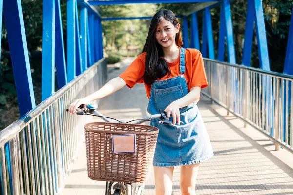 Długie Włosy Dziewczyna Pomarańczowym Shirt Dżinsy Skoczek Chodzenie Rowerem Niebieski — Zdjęcie stockowe